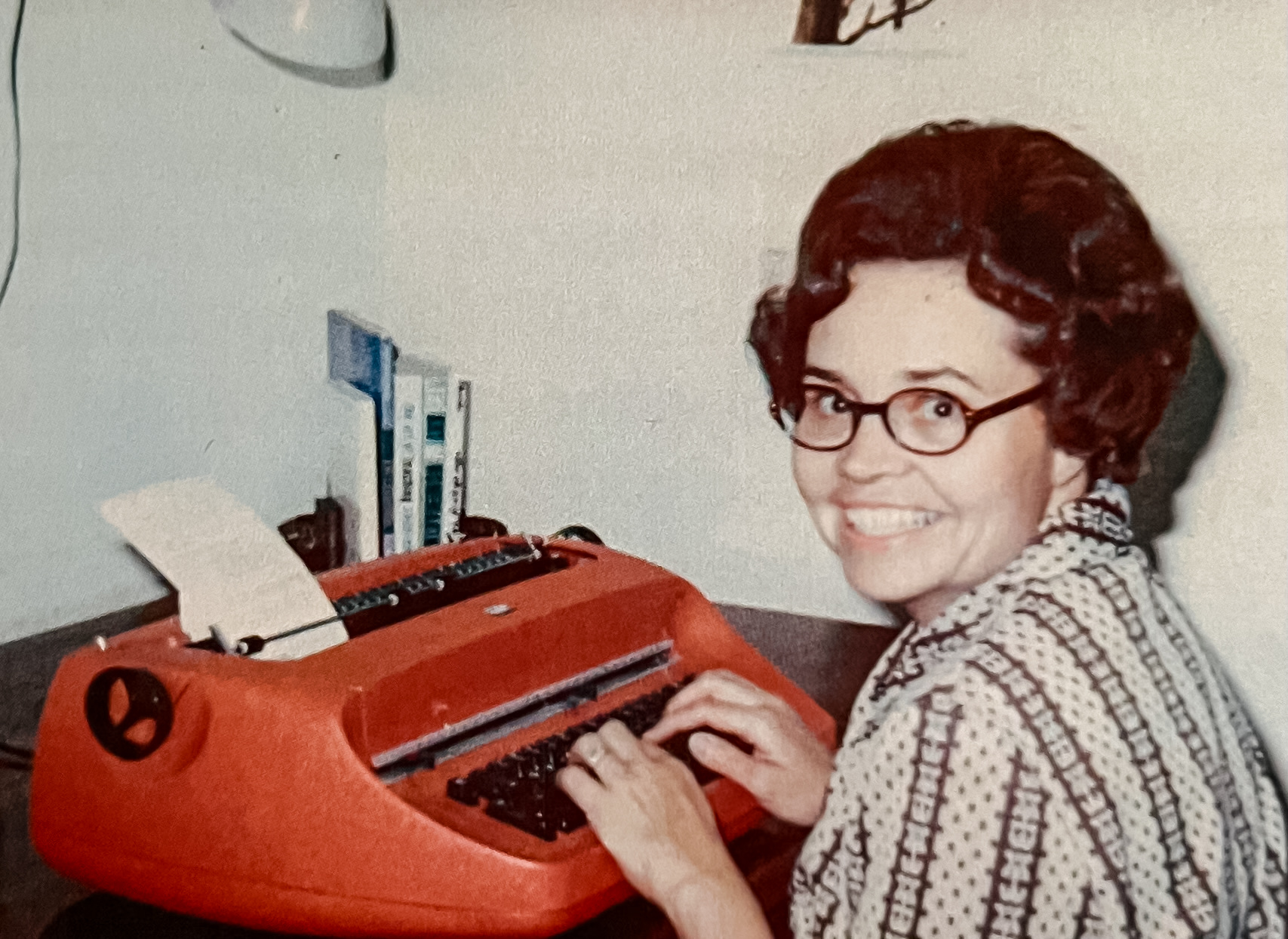 Daryl Hoole Sitting at a desk with her beloved red typewriter