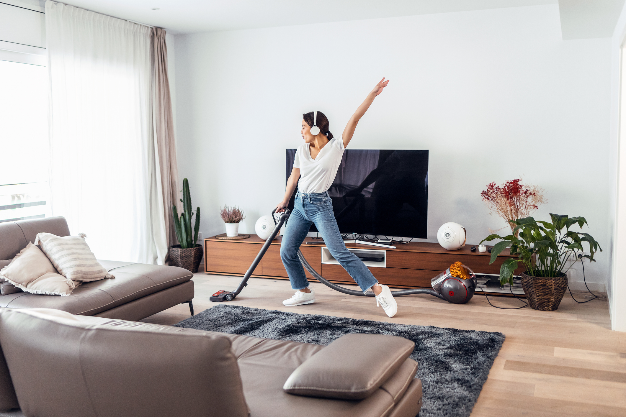 Woman cleaning while listening to music. Remember to skim before you scour (aka deep clean!)